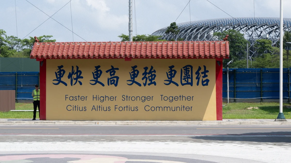 Sign with Chinese characters and the motto “Faster Higher Stronger Together” in front of a stadium structure.