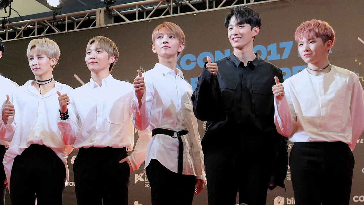 Five members of SEVENTEEN’s Vocal Team pose onstage, including Jeonghan and Joshua