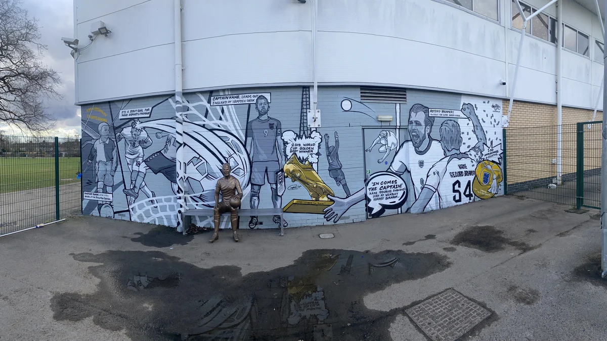 Estatua de Harry Kane frente a un mural exterior sobre su carrera