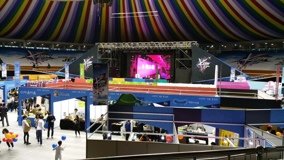 Wide view of a stage and booths inside the KCON Jeju 2015 venue
