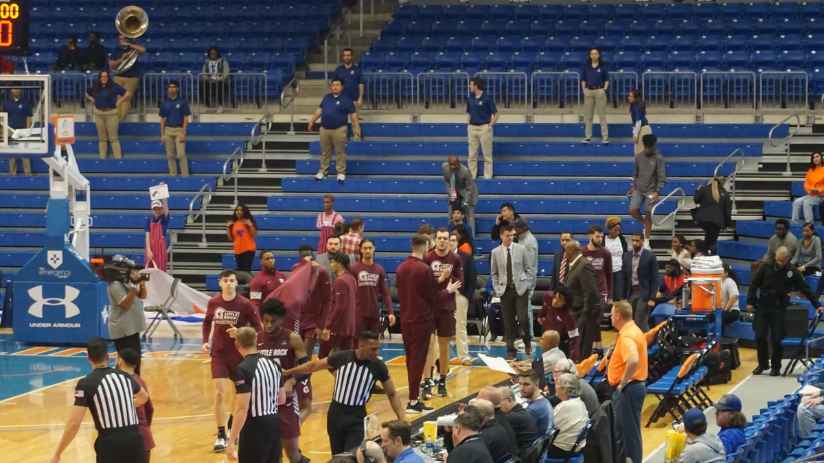 Jogadores de Little Rock reunidos junto à lateral da quadra antes de uma partida de basquete
