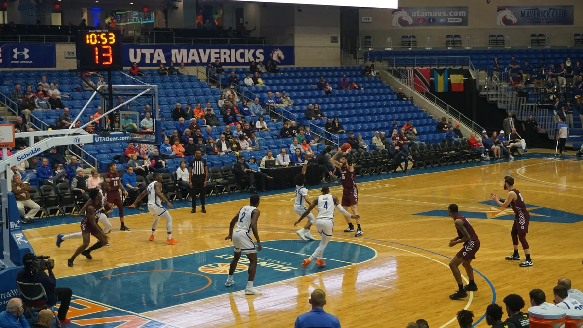 Jogador de Little Rock arremessa enquanto atletas de UT Arlington defendem o garrafão