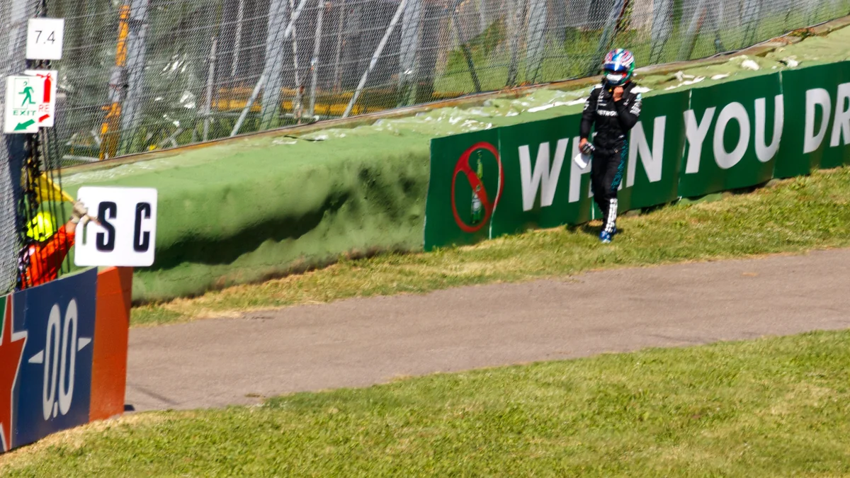Kimi Antonelli walks beside the safety barriers at a racetrack
