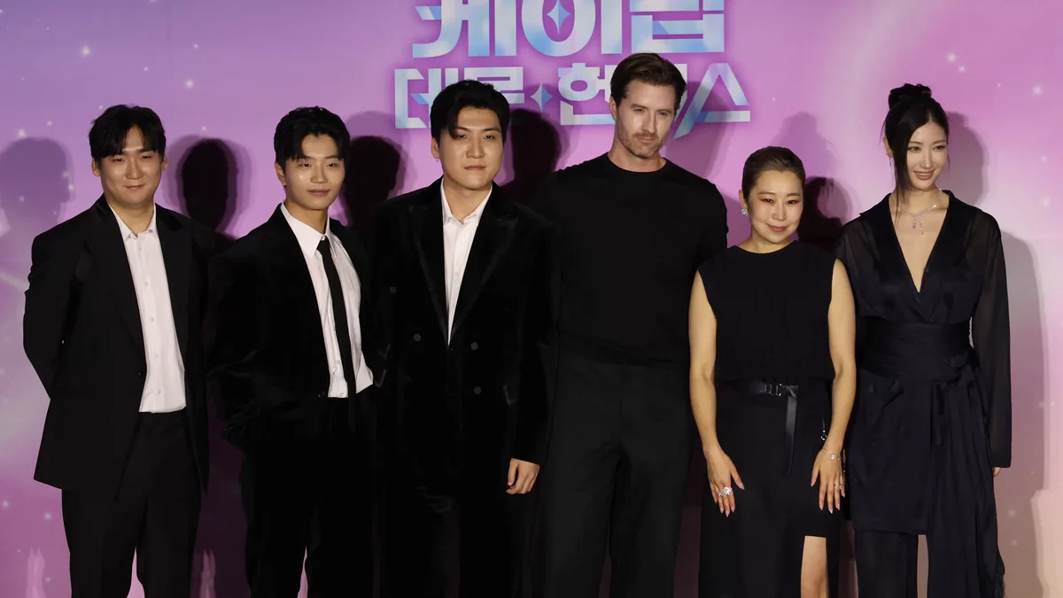 Six membres de l’équipe de KPop Demon Hunters posent devant un fond rose