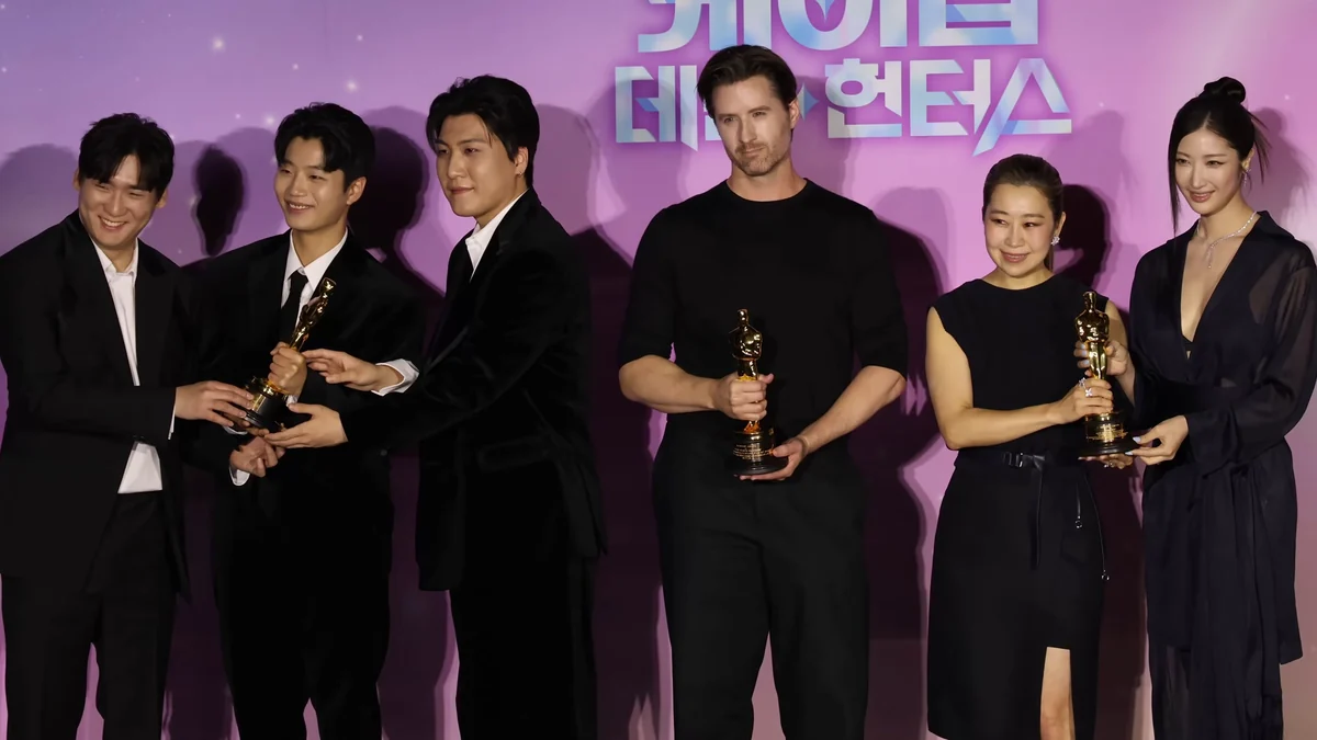 Un groupe de six personnes pose avec des statuettes dorées devant un fond rose