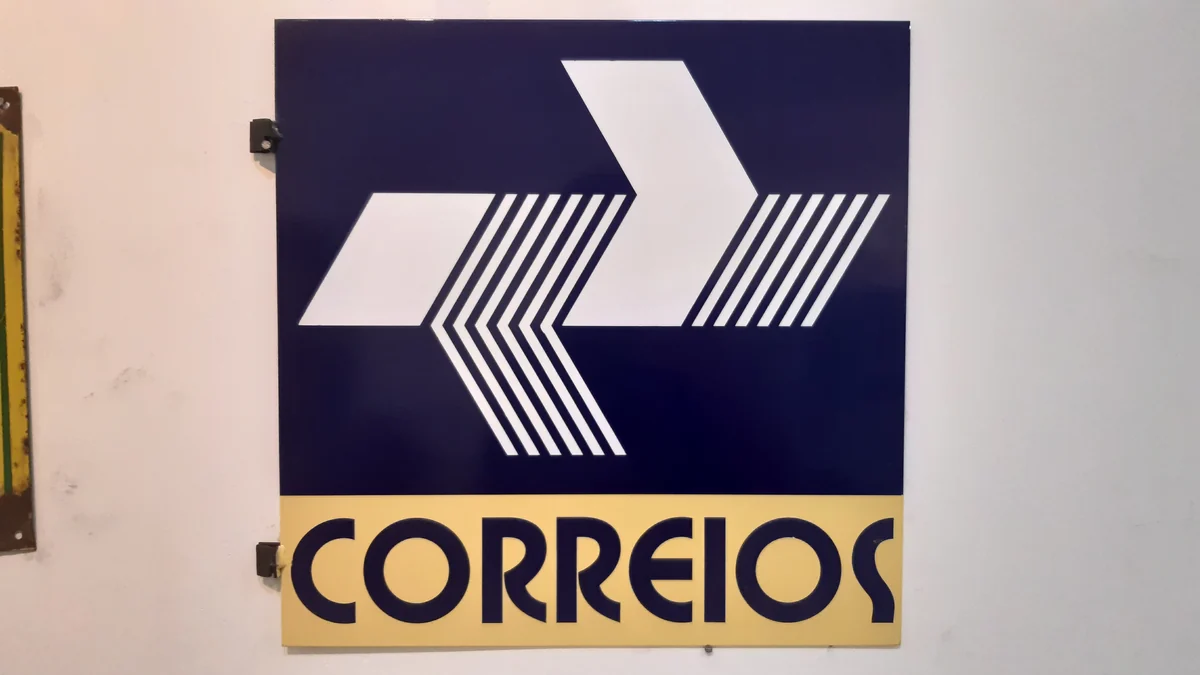 Letrero azul y amarillo con un símbolo blanco y la palabra «Correios».