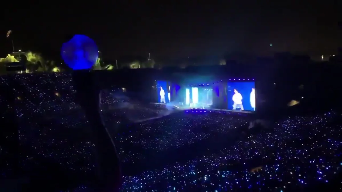 Stadium filled with blue lights in front of a BTS concert stage