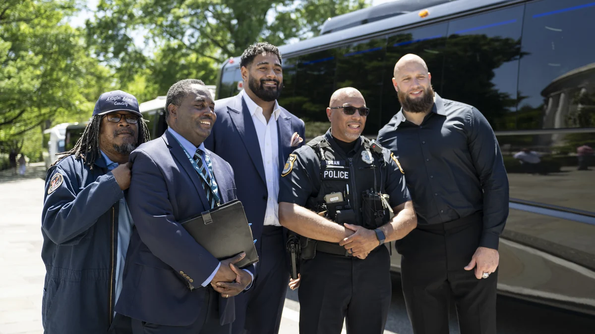Jordan Mailata et Lane Johnson posent avec trois hommes devant un autocar