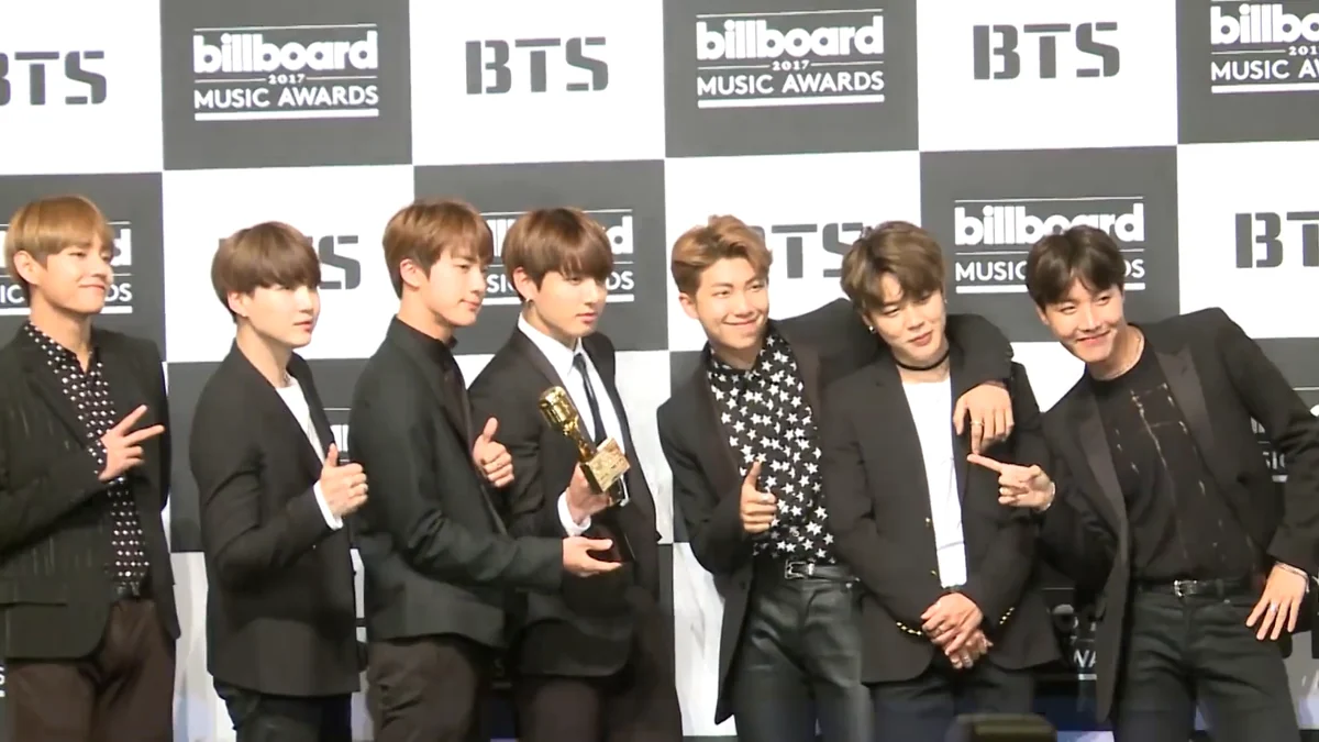 Los siete integrantes de BTS posan ante un panel de los Billboard Music Awards; uno sostiene un trofeo