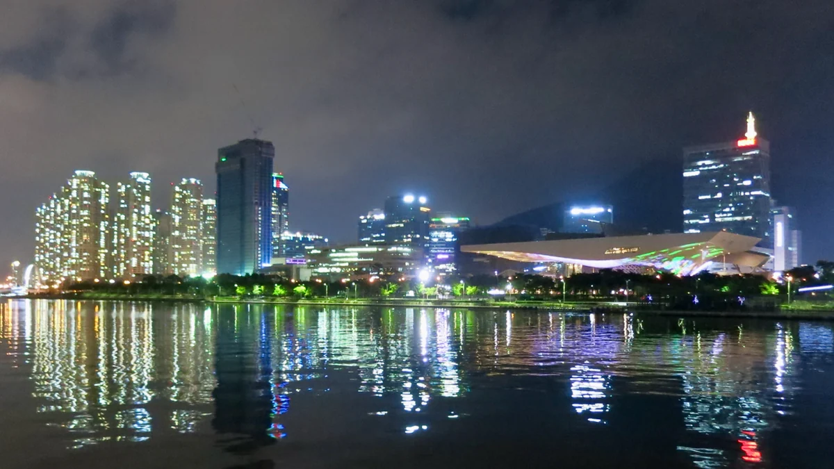 Busan Cinema Center iluminado à noite diante da água e dos edifícios de Centum City