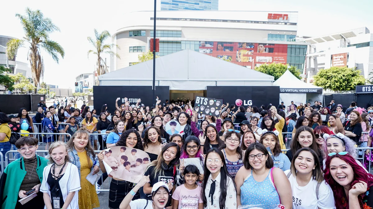 Groupe de fans de BTS réuni devant un espace événementiel extérieur