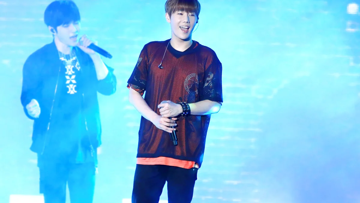 Cantor Kim Sung-kyu segura um microfone em palco iluminado de azul