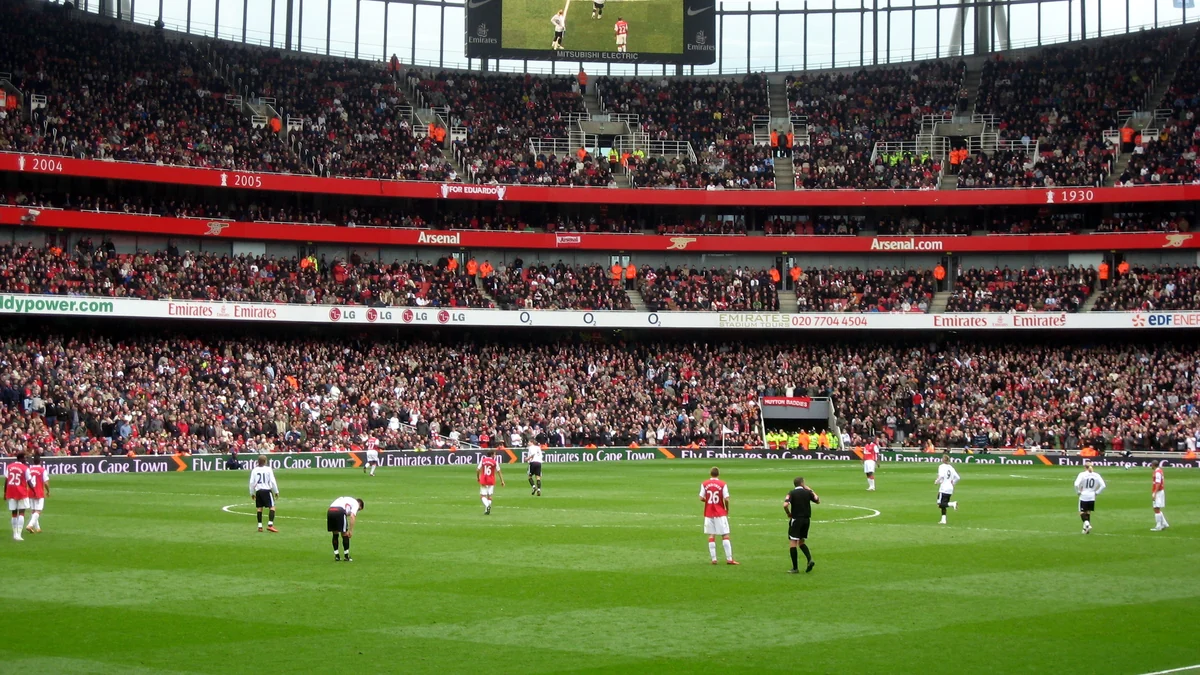 Jugadores de Arsenal y Liverpool en el campo ante gradas llenas