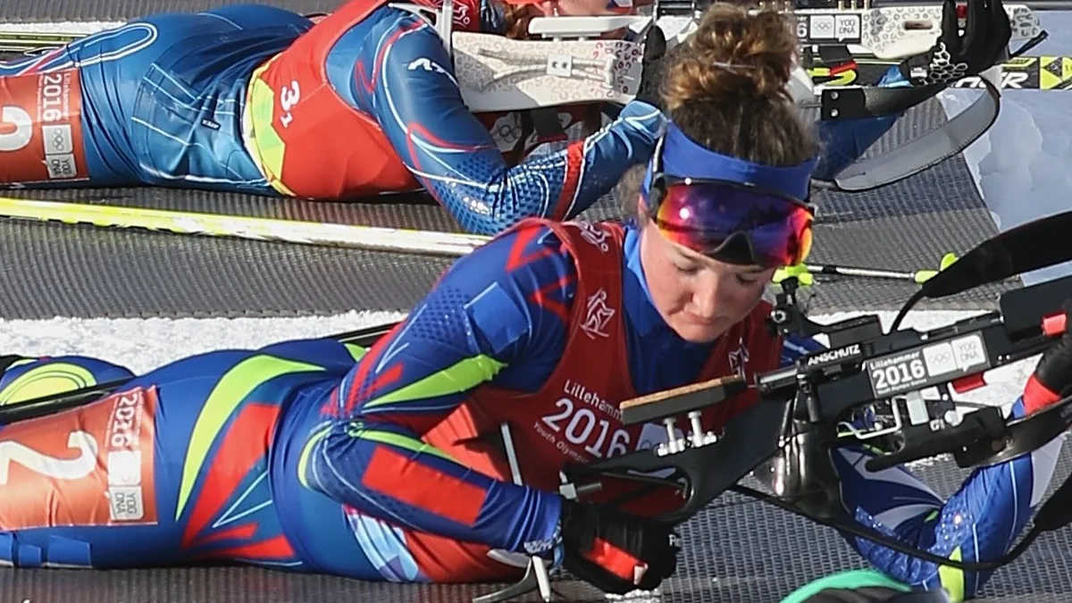 Lou Jeanmonnot deitada na neve durante uma sessão de tiro do biathlon
