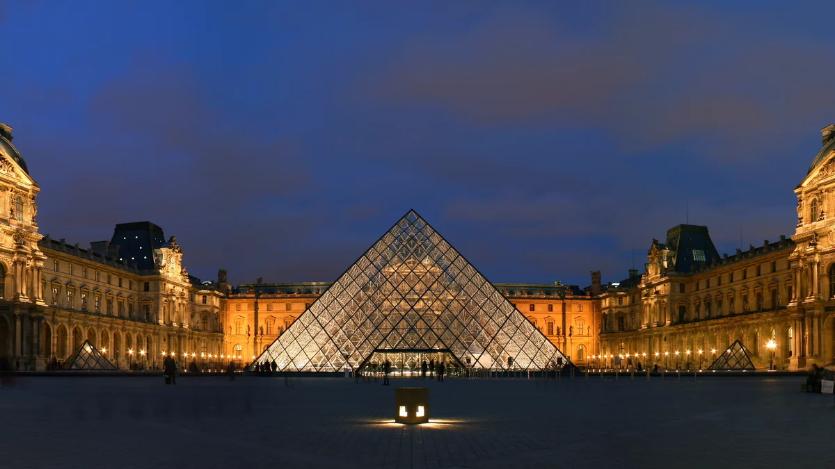 Pirâmide de vidro iluminada no pátio do Louvre ao anoitecer
