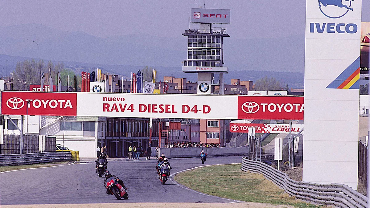 Des motocyclistes prennent un virage du circuit de Jarama sous des panneaux publicitaires