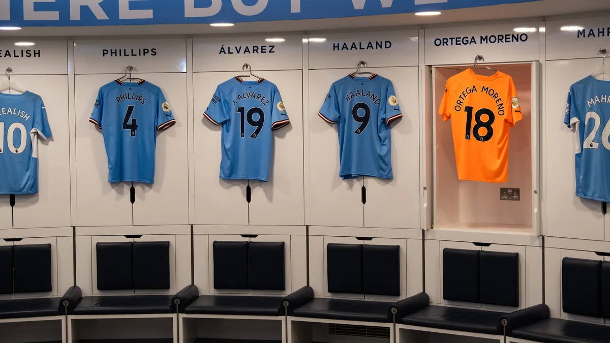 Camisas azuis de Phillips, Álvarez e Haaland e uniforme laranja de Ortega no vestiário do Manchester City