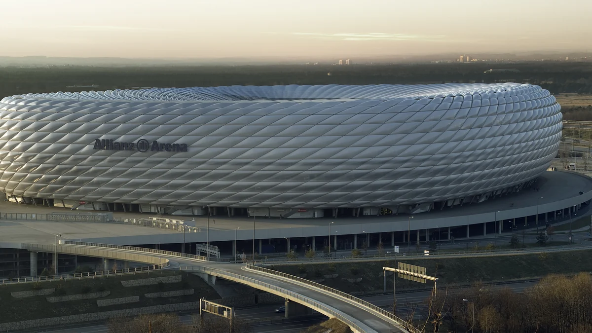 Exterior view of Allianz Arena, with its silver facade, access roads and the horizon in the background.