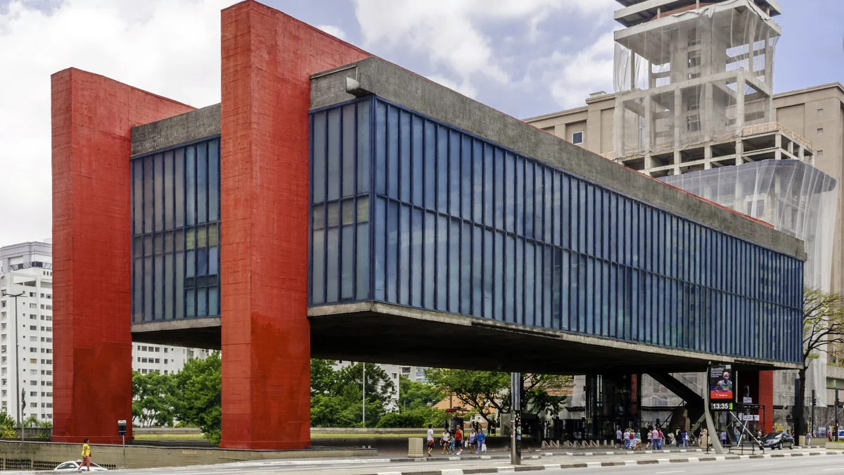 Edifício do MASP com volume envidraçado suspenso entre pilares vermelhos