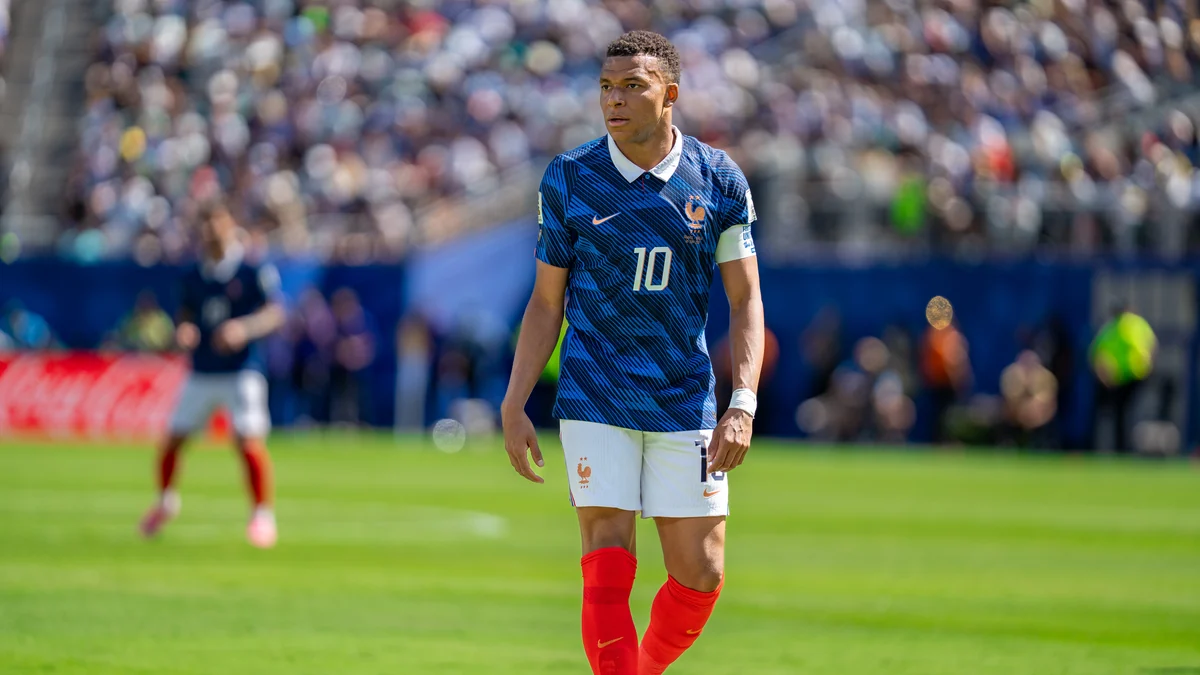 Kylian Mbappé marche sur la pelouse avec le maillot bleu numéro 10 de la France.