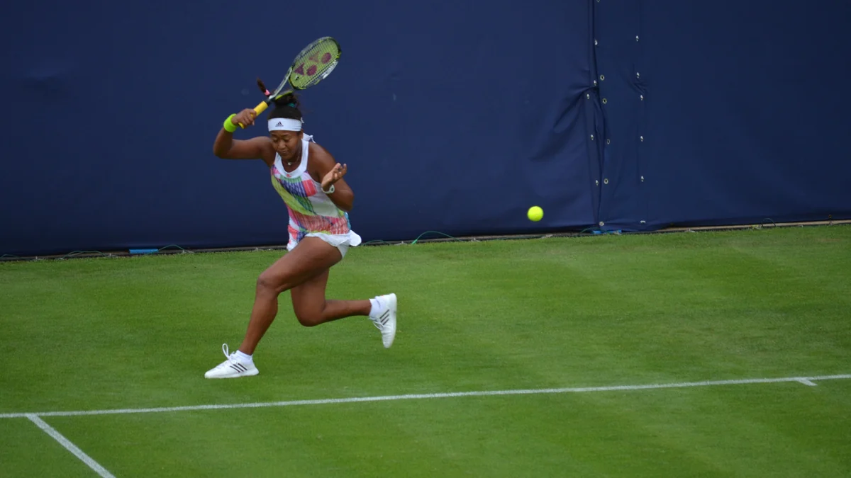 Naomi Osaka runs toward the ball during a match on a grass court