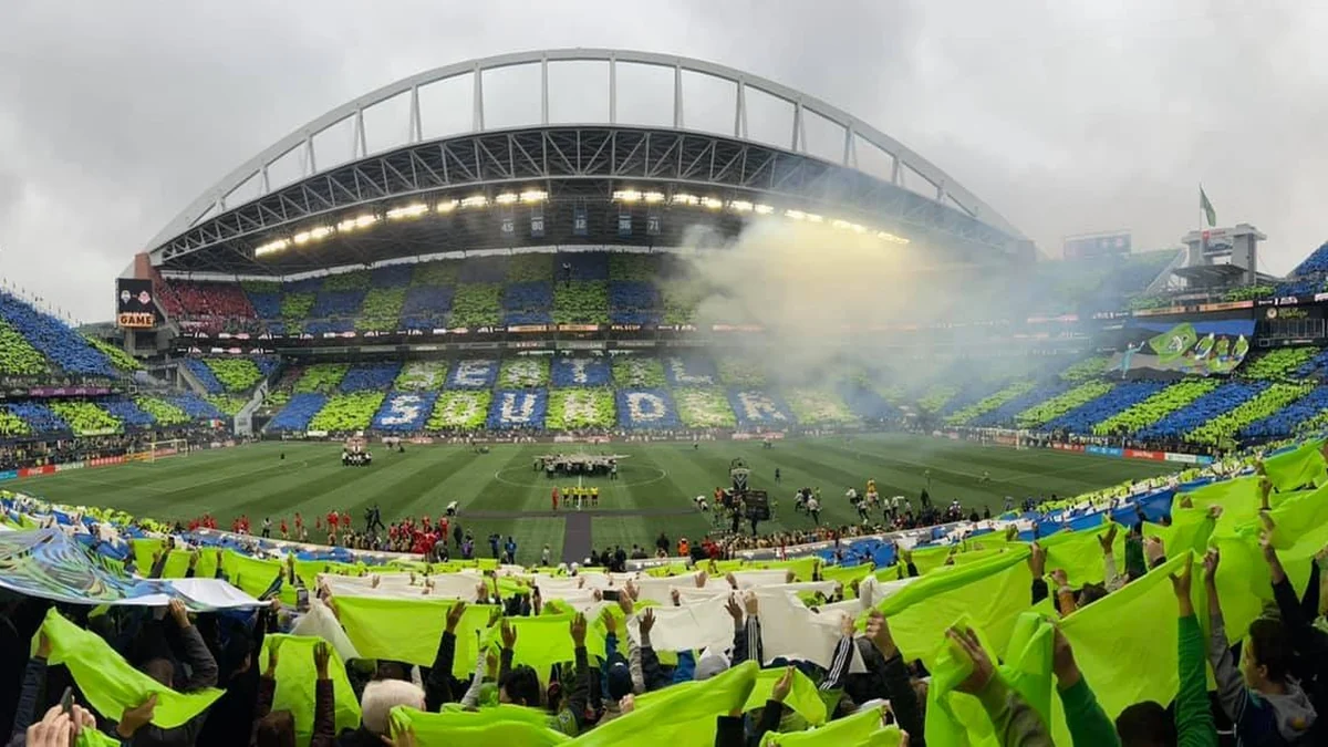 Supporters raise green, blue and white panels in a soccer stadium before a match.