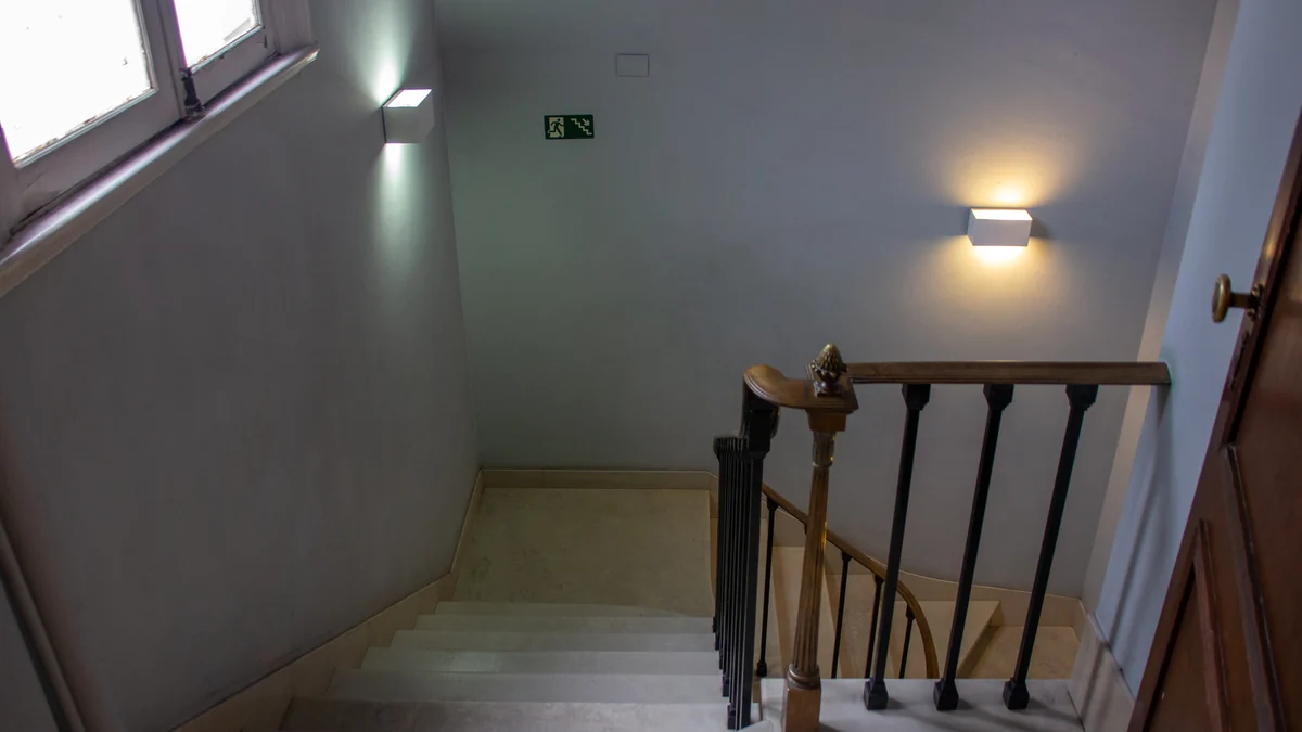Escalier intérieur aux marches claires, avec main courante en bois et balustres foncés