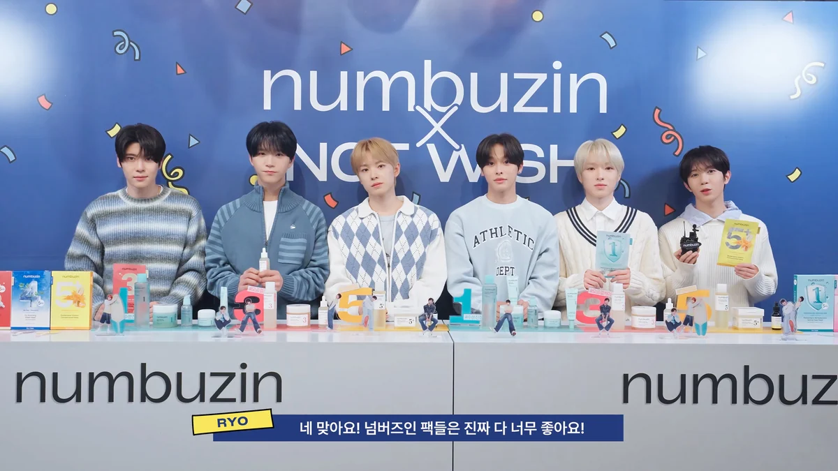 Los seis integrantes de NCT WISH posan detrás de un mostrador con cosméticos; abajo aparece una franja de subtítulos en coreano.