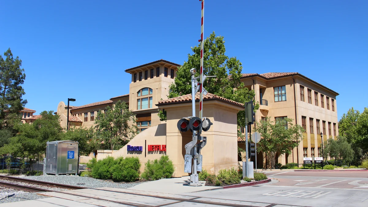 Office building with Roku and Netflix signs beside a railroad crossing