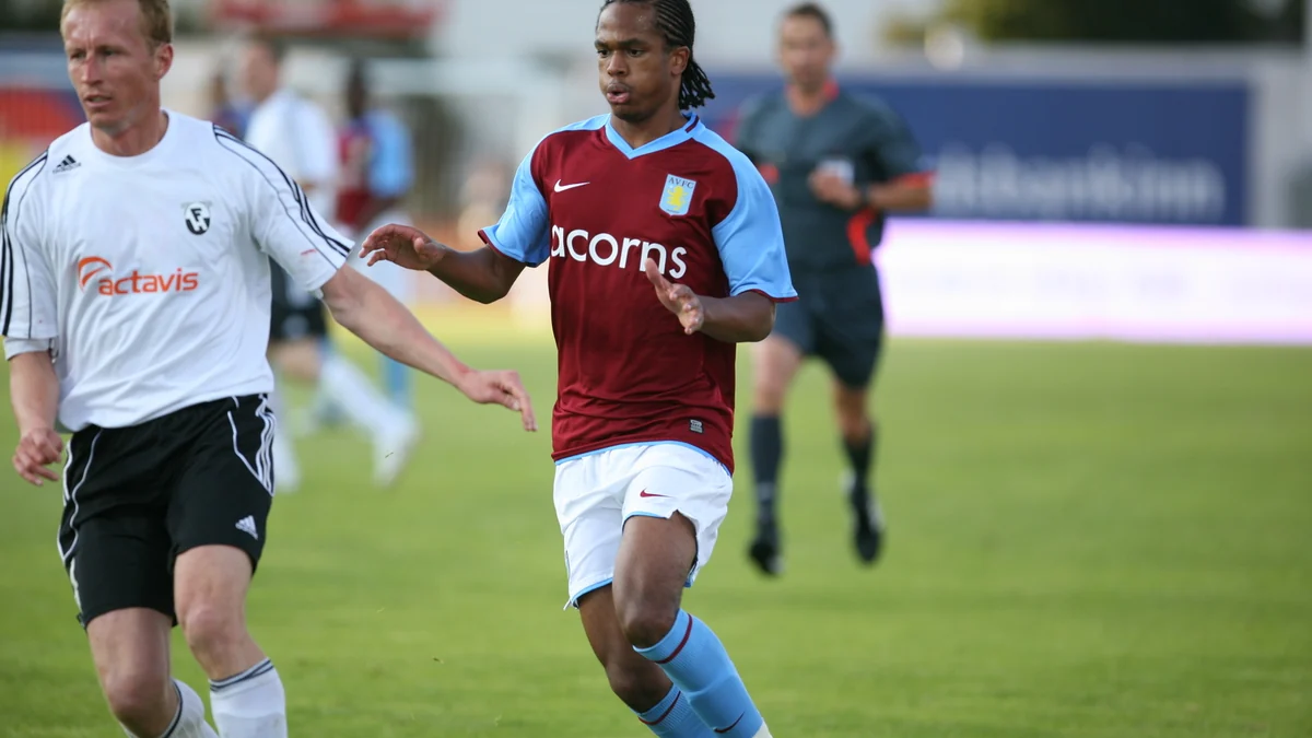 Jogador do Aston Villa corre pelo campo ao lado de um adversário de branco