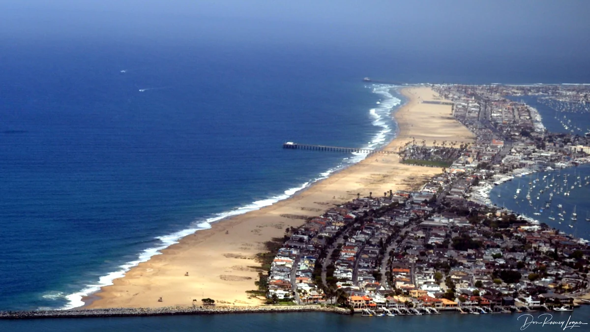 Vue aérienne de Balboa Peninsula avec l’océan, la plage, des quartiers, une jetée et des bateaux dans le port