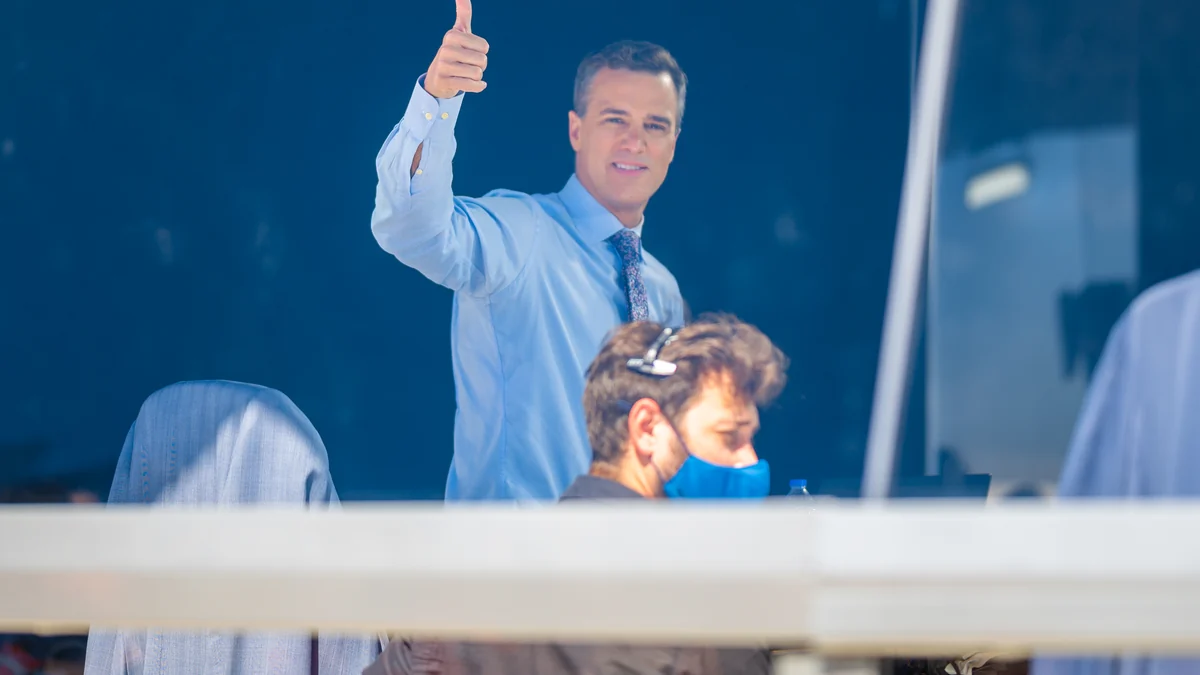 Homme faisant un signe du pouce dans une cabine de diffusion, avec une autre personne au premier plan