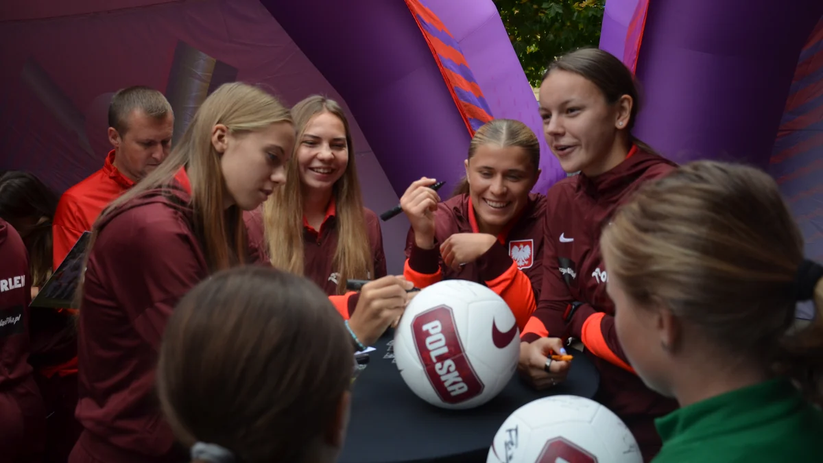 Jugadoras de la selección femenina sub-20 de Polonia firman balones para jóvenes aficionadas.