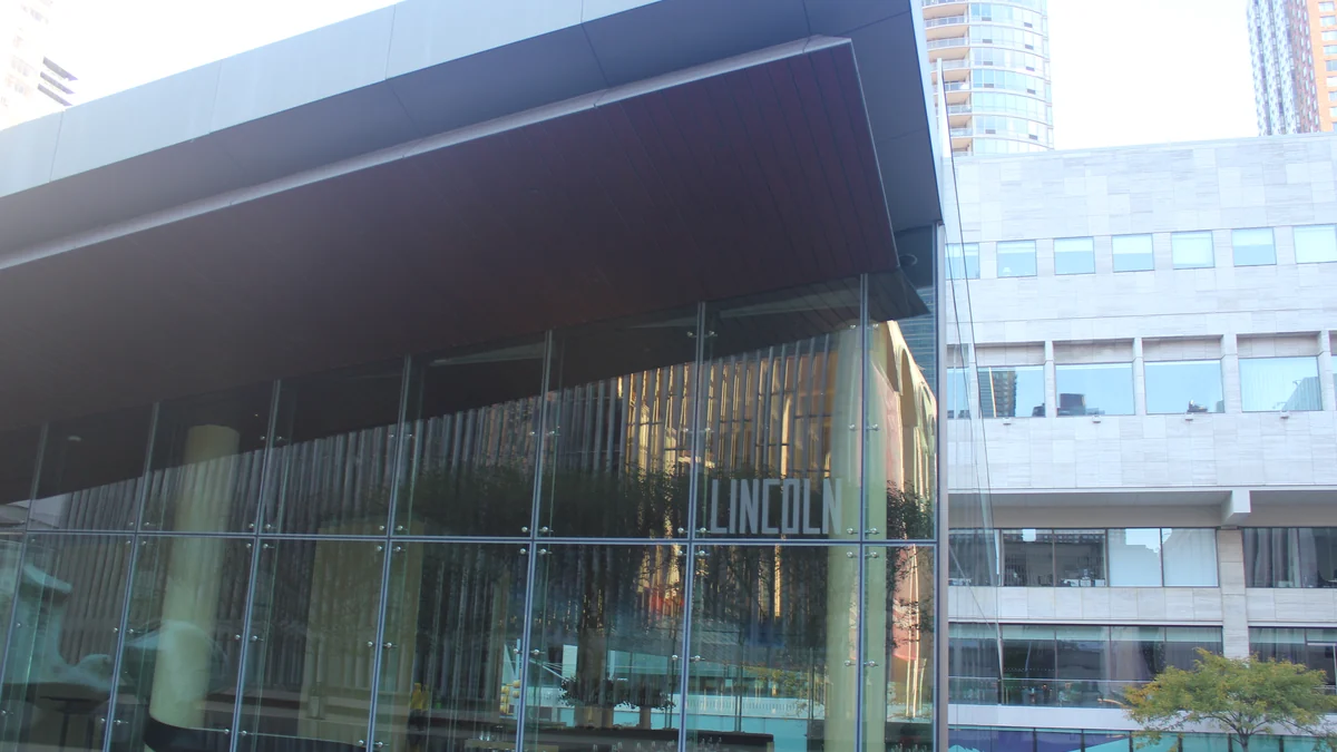 Angular glass façade at Lincoln Center, with the Lincoln name visible by the entrance