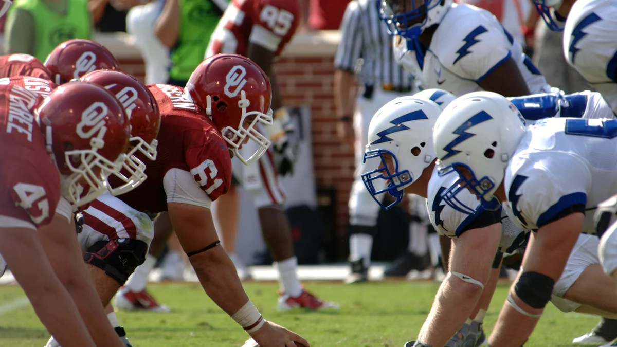 Oklahoma players in crimson uniforms line up opposite the Air Force defense.