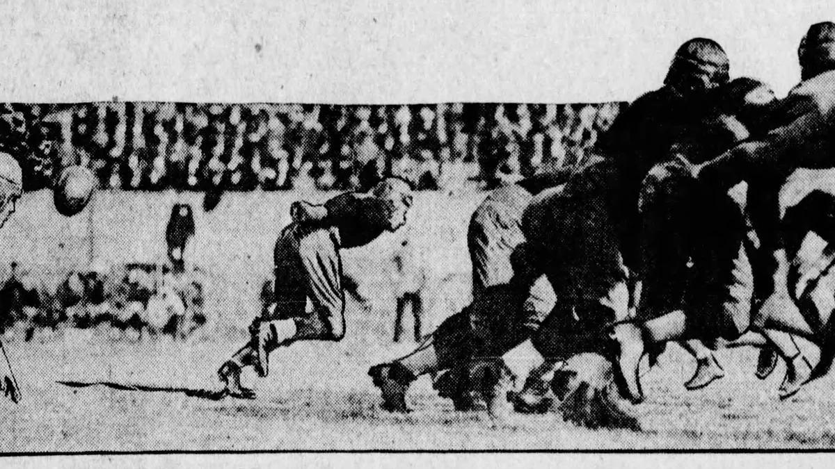 Football players contest a play in a historical black-and-white photograph.
