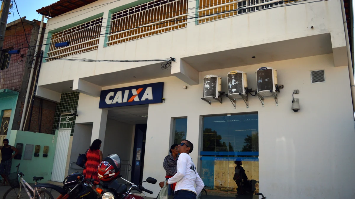 Exterior of a Caixa branch, with people and motorcycles in front of the entrance.
