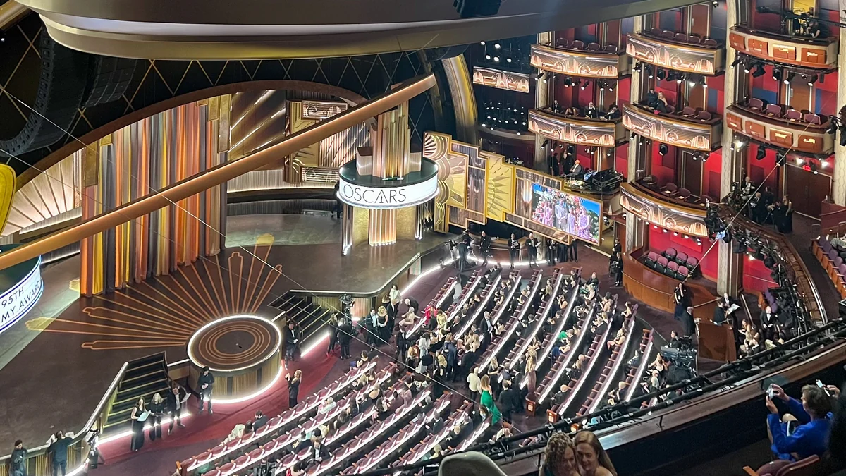 Elevated view of a theater with a gold Oscars stage, audience seating, boxes and filming equipment.