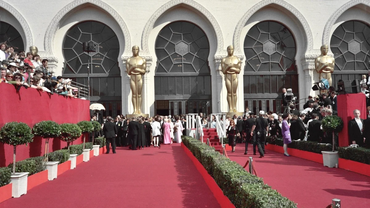 Tapis rouge des Oscars devant des arches et de grandes statuettes dorées
