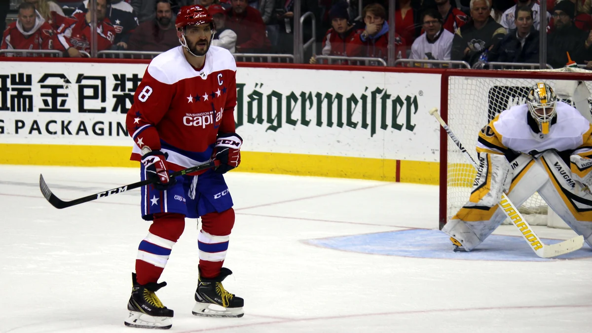 Alex Ovechkin en tenue rouge des Capitals sur la glace devant un gardien des Pittsburgh Penguins