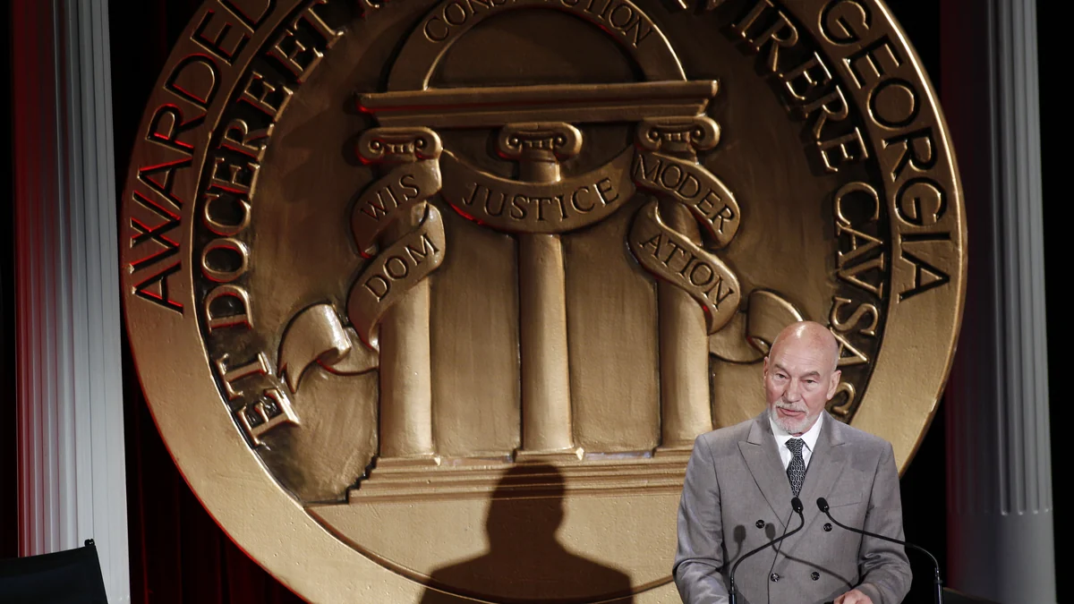 Patrick Stewart parle devant un grand médaillon doré des Peabody Awards