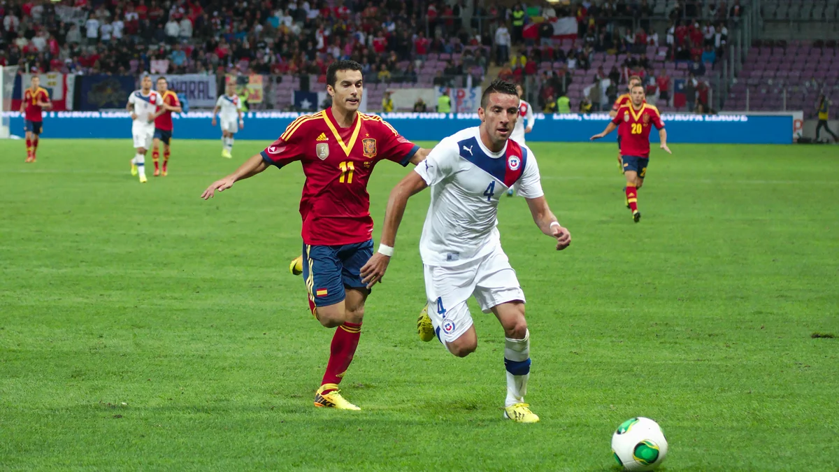 Pedro Rodríguez runs behind Mauricio Isla during a match between Spain and Chile