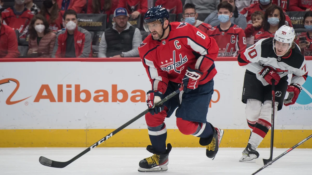 Alex Ovechkin patina con el disco mientras lo sigue un jugador de los New Jersey Devils