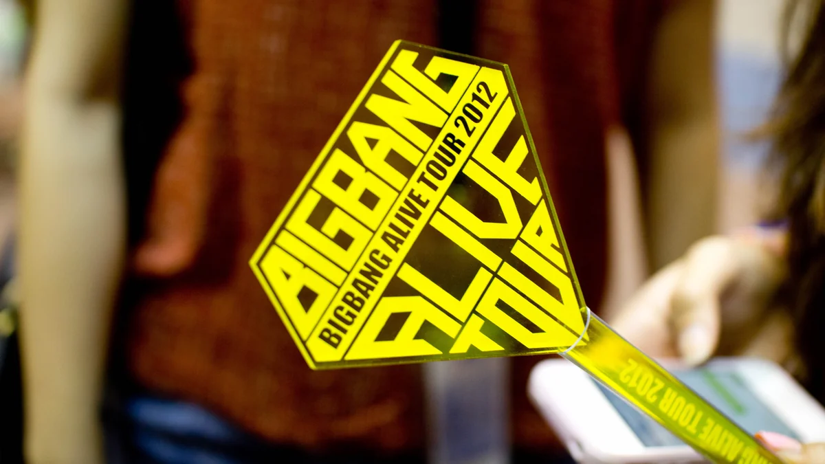 Lightstick amarillo de la gira Alive de BigBang sostenido ante un mostrador