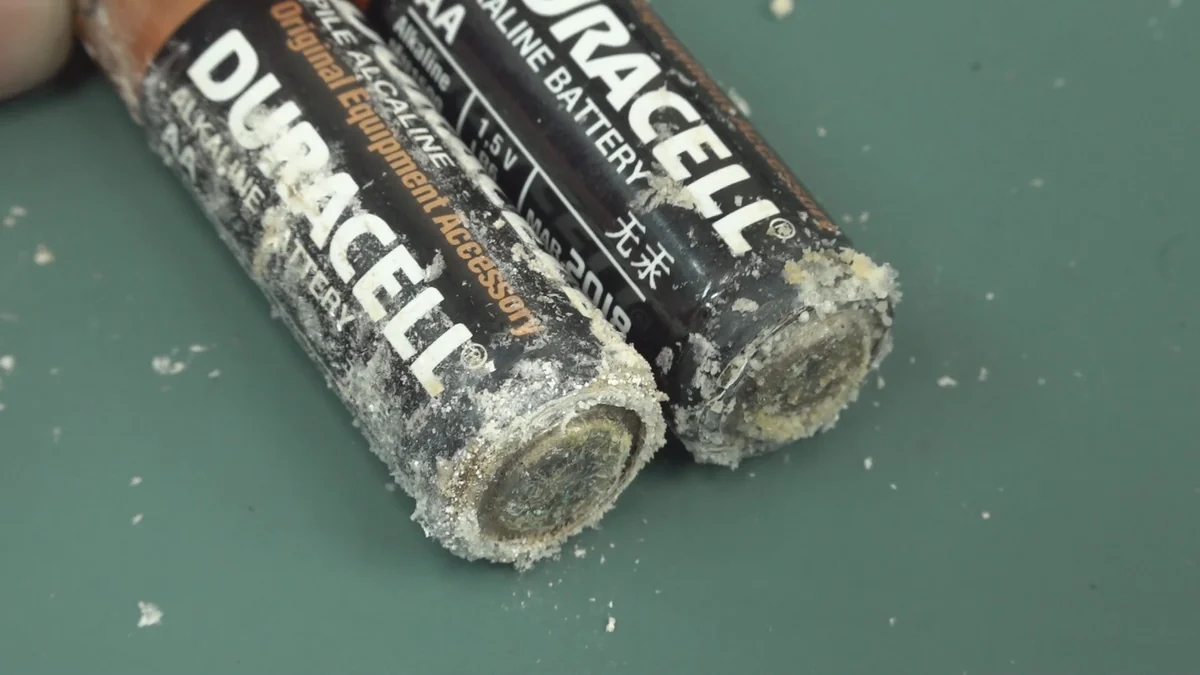 Two AA alkaline batteries with crystallized material around their terminals