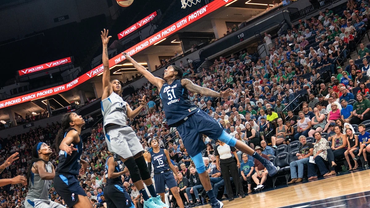 Una jugadora de Minnesota Lynx lanza cerca de la canasta mientras una rival de Atlanta Dream intenta bloquearla.