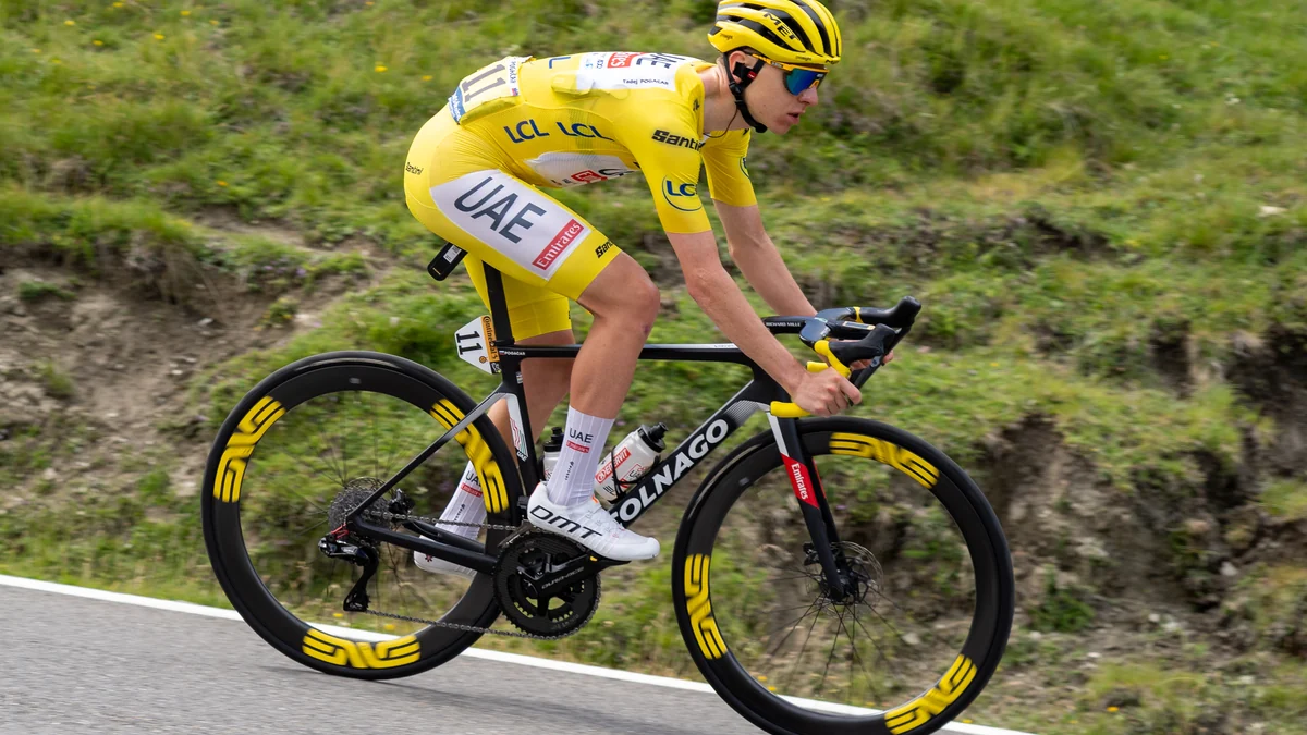 Tadej Pogačar rides alone in a yellow jersey and helmet on a mountain road.