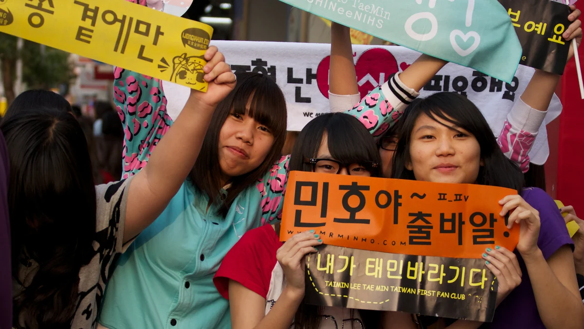 Groupe de fans de K-pop tenant des banderoles colorées avec du texte coréen