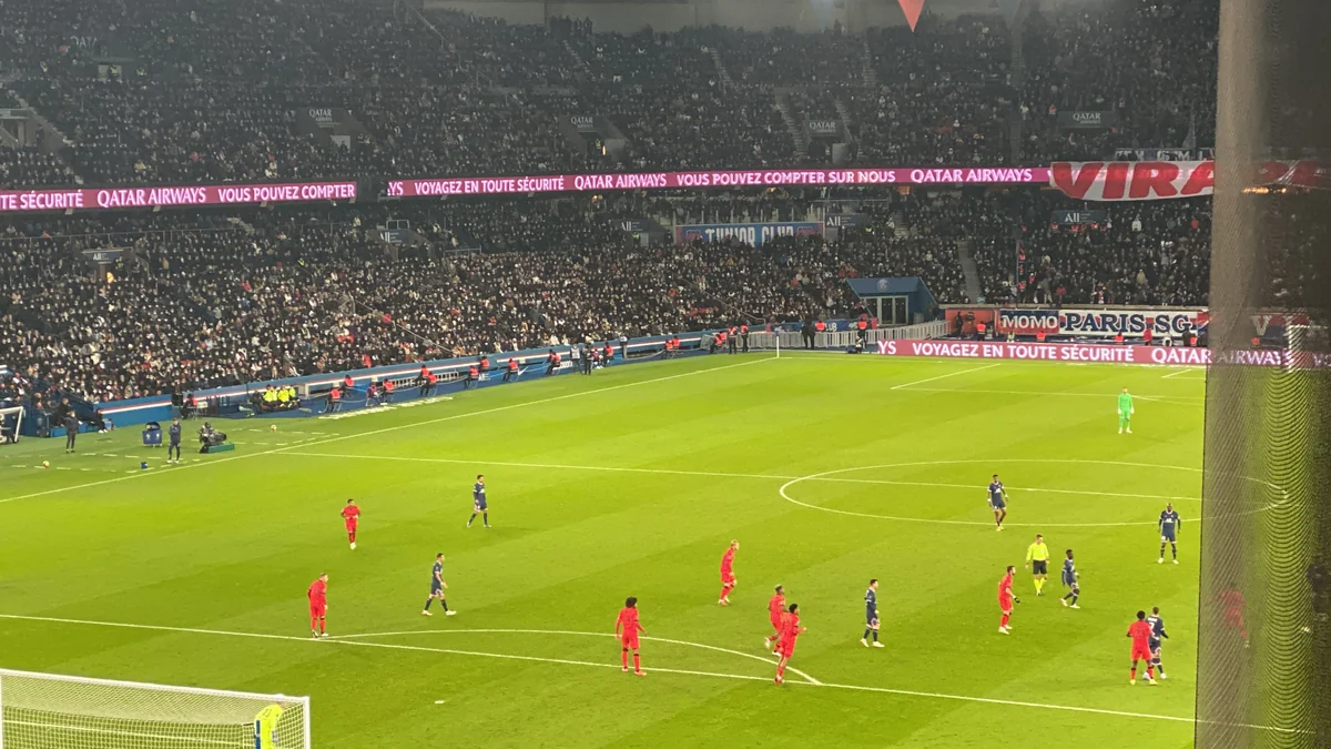 Jugadores con uniformes azules y rojos sobre el campo del Parc des Princes