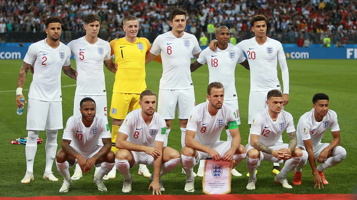 Onze jogadores da seleção inglesa posam em duas fileiras no gramado, usando uniformes brancos.